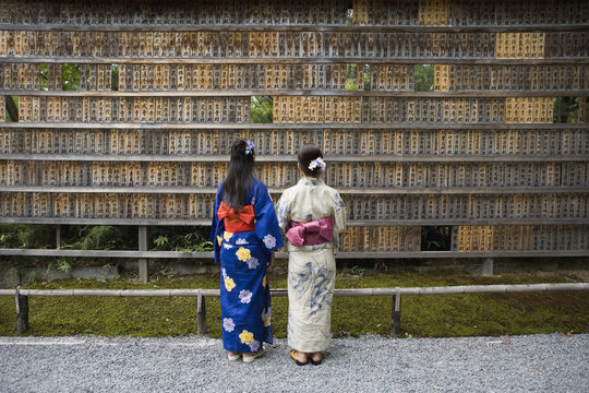 Rear view of women standing in front of prayer blocks at a shrine