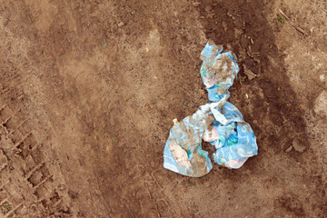 Dirty and tattered rag lying in the dirt. On the land footprint