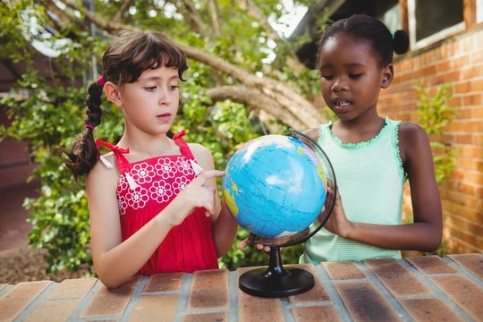 Girls pointing at a globe