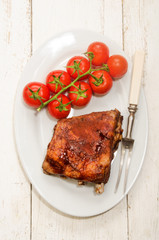 crispy marinated ribs and fresh tomatoes on an oval plate