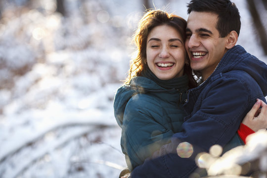 Cheerful young couple embracing on field during winter