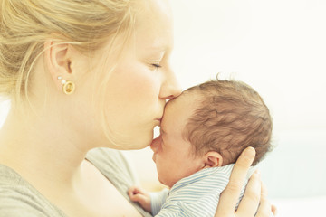 Mother kissing her newborn child