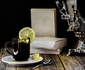 old samovar and tea Cup with lemon on wooden background