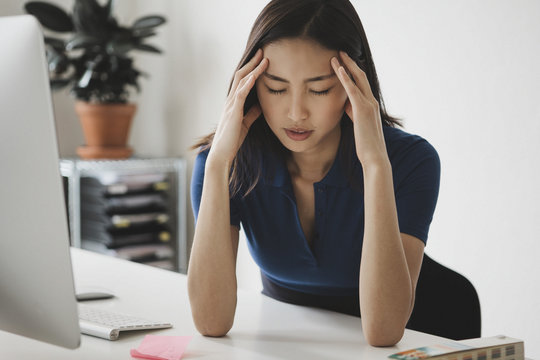 Young businesswoman suffering from headache at desk in office