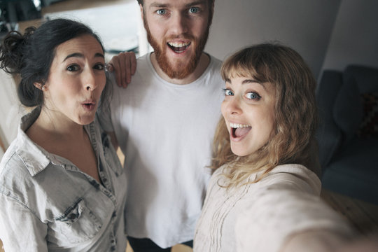 Portrait of young man with female friends having fun at home