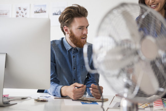 Young businessman communicating with female colleague at desk