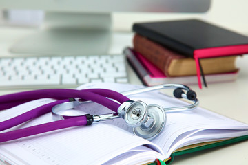 Stethoscope lying on a table on an open book