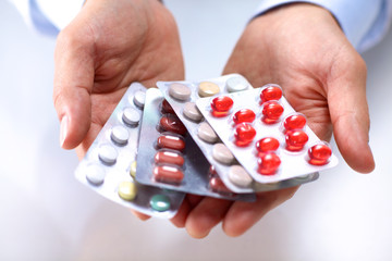 A young doctor holds the patient's hand with pills