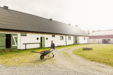 Woman pushing wheelbarrow in farm