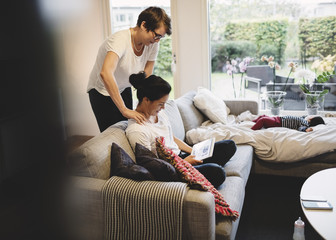 Woman massaging girlfriend using tablet in living room at home