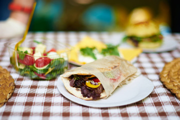 Pita sandwich with grilled meat with other food outdoor