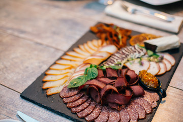 Antipasto catering platter with salami and meat on a wooden background