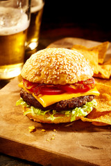Cheeseburger with chips and beer in background
