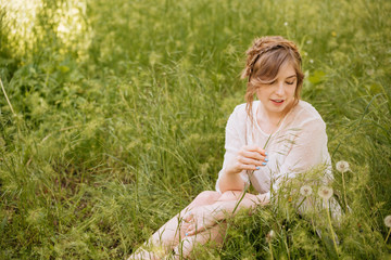 Naklejka na ściany i meble Charming sensual young woman sitting on grass with dandelions