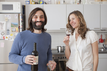 Happy couple enjoying red wine in kitchen