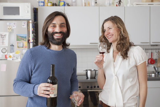 Happy couple enjoying red wine in kitchen