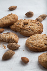 Cookies pile with chocolate chip and almond on light textile background. Delicious morning snacks for breakfast, brunch and lunch. Appetizing, healthy and fast food