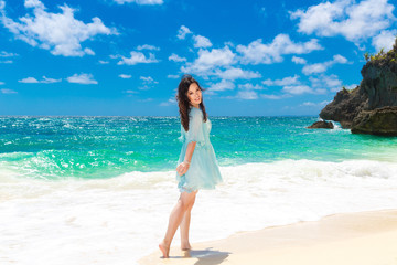 Fototapeta na wymiar Young beautiful Asian girl in blue dress on the beach of a trop