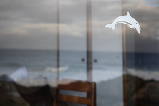 View of rough sea through window with dolphin decal on it