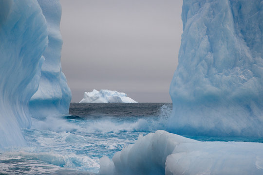 Blue-tinged icebergs frame a distant iceberg