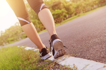 Closeup on shoe athlete runner feet running on road. woman fitness jog workout wellness concept at sunrise morning.