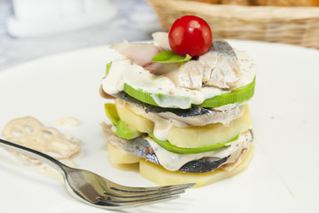 Herring salad with avocado sauce on a plate in a restaurant