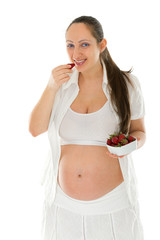 Pregnant young woman eating strawberries and smiling. Isolated on white background