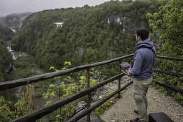 Fototapeta na wymiar Man is operating the drone with a Plitvice waterfalls background