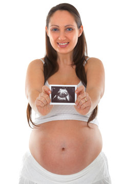 Pregnant woman holding ultrasound scan photo in front of her chest. Isolated on white background. Focus on photo