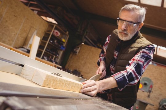 Carpenter sawing a plank of wood