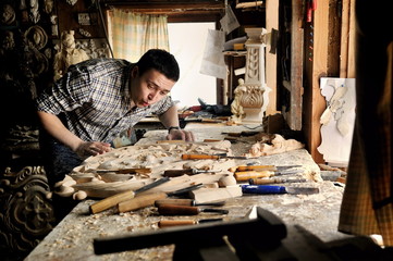 Carver in workshop of wood carving blow off sawdust