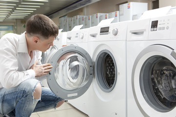 Young man buying new washing machine