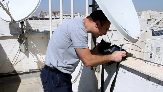 Technician  adjusting  of a satellite television plate with satellite  channels finder