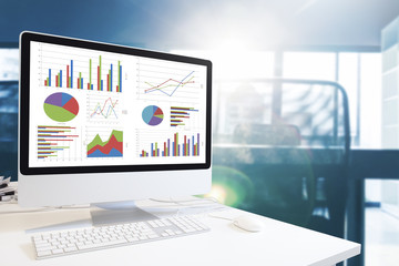 Modern computer with keyboard and mouse on table showing charts