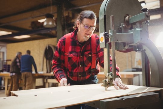 Carpenter sawing a plank of wood