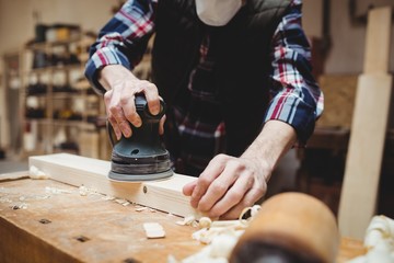 Carpenter sanding down a plank of wood