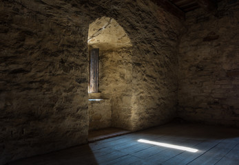 Dark room with stone walls window and wooden staircase