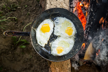eggs fried in a cast iron pan on the campfire