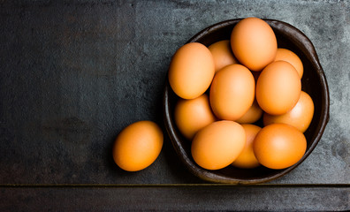 Eggs in clay bowl on black background