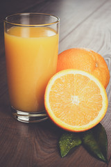 fresh orange and glass with juice on the brown wooden table