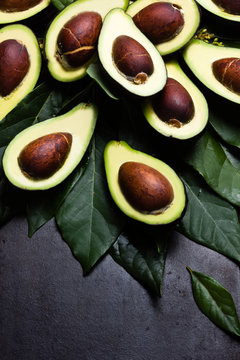 Fresh avocado with leaves on black background