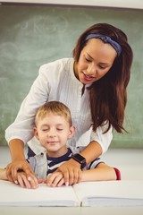 Teacher helping a boy with his homework in classroom