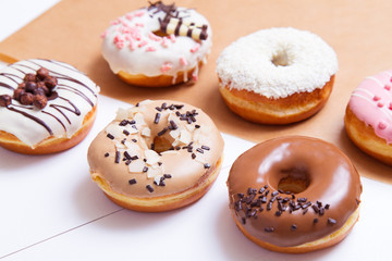 Colored delicious donuts with sprinkles on a white wooden background