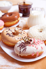 Colored delicious donuts with coffee and milk on a white wooden background