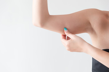 二の腕を摘む女性・白バック