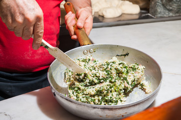 A cook mixing rice, spinach, jam and parmesan cheese to make the typical sicilian arancini