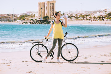 Fototapeta na wymiar carefree woman with bicycle riding on beach sand having fun and