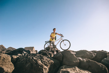 Fototapeta na wymiar sports girl cyclist stands on the stone beach
