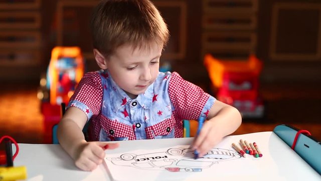 Boy Paints the Police Car With Crayons Sitting at Table
