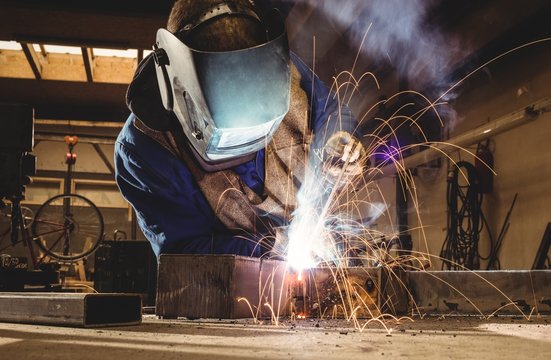 Welder cutting metal with grinder in workshop